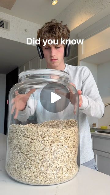 a young man wearing headphones standing in front of a jar filled with oatmeal