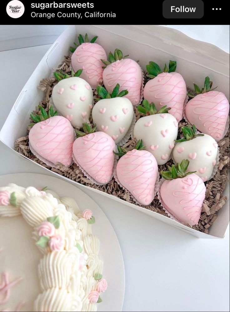 a box filled with white chocolate covered strawberries next to a plate full of cake