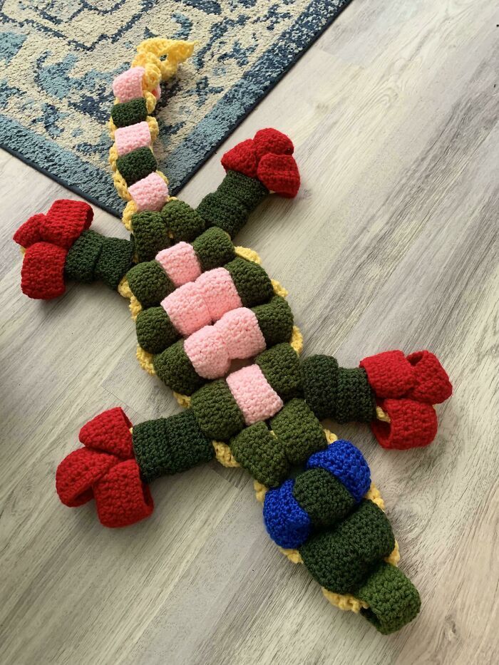 a crocheted toy laying on top of a wooden floor next to a rug