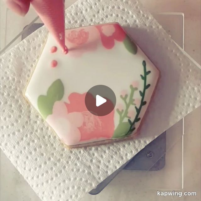 someone is decorating a decorated cookie with flowers and leaves on paper towel napkins