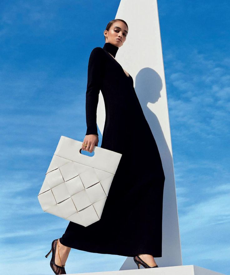 a woman in a black dress carrying a white bag