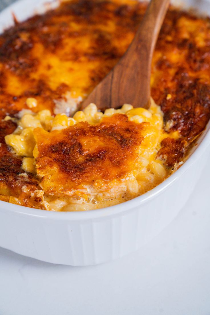 a casserole dish is shown with a wooden spoon in it and cheese on top