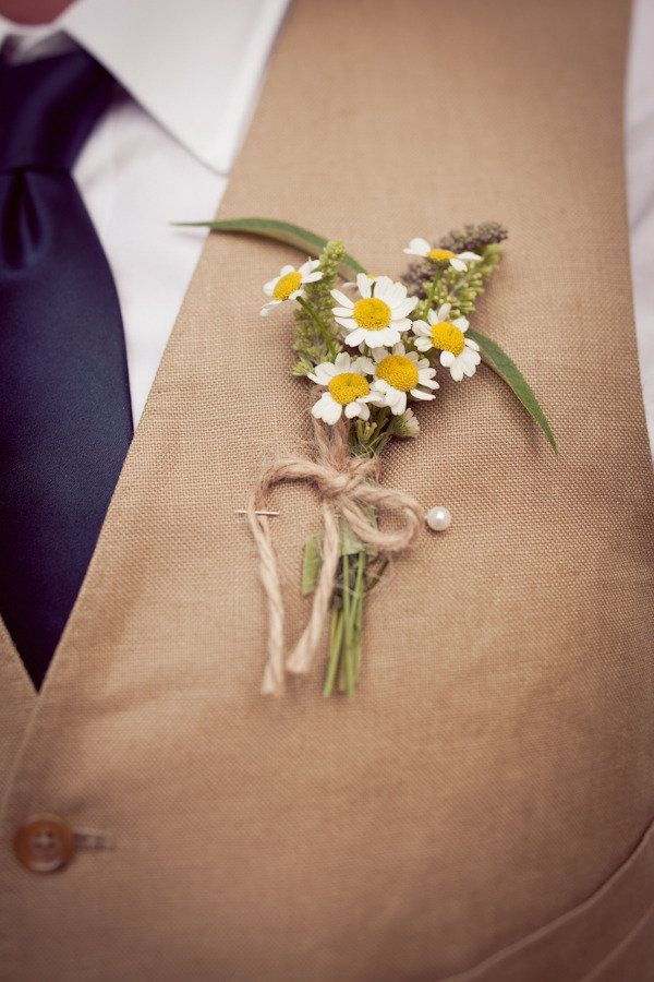 a boutonniere with daisies and other flowers tied to the lapel