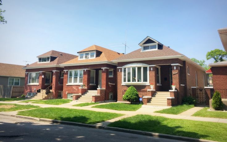 a row of red brick houses with green grass in front