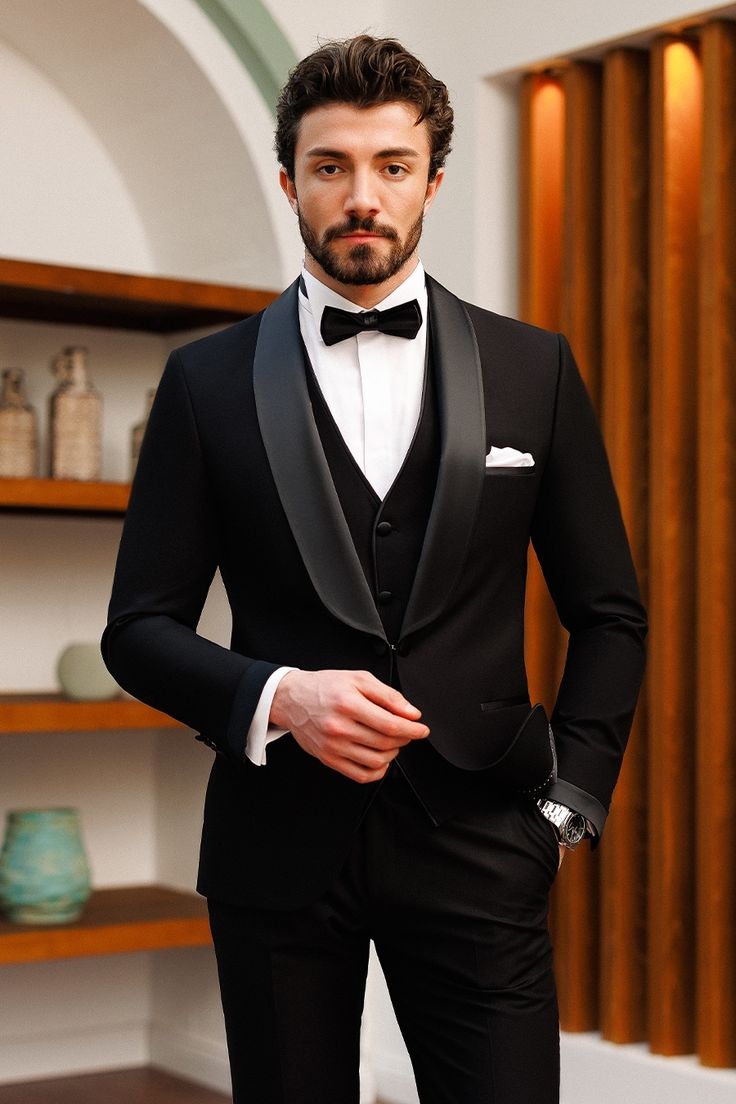 a man in a tuxedo poses for the camera with his hands on his hips