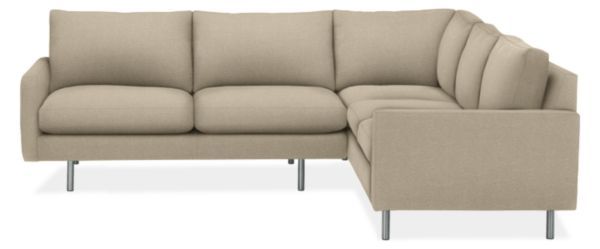 a beige sectional couch with a footstool and arm rest on the right side