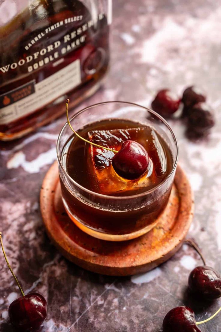 a glass bowl filled with cherries on top of a wooden plate