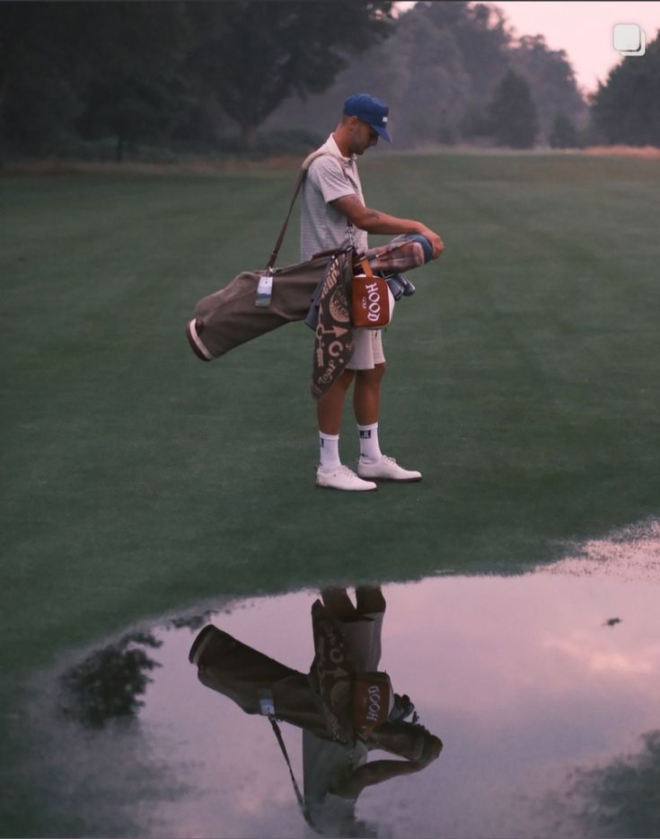 a man standing on top of a green field next to a puddle