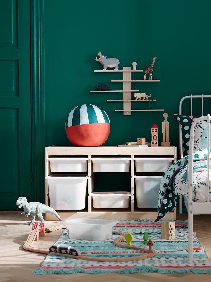 a child's bedroom with green walls and toys on the floor in front of it