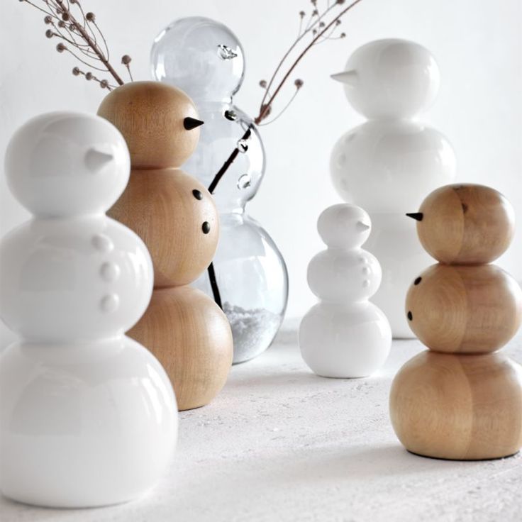 three snowmen made out of wood sitting next to vases with flowers in them