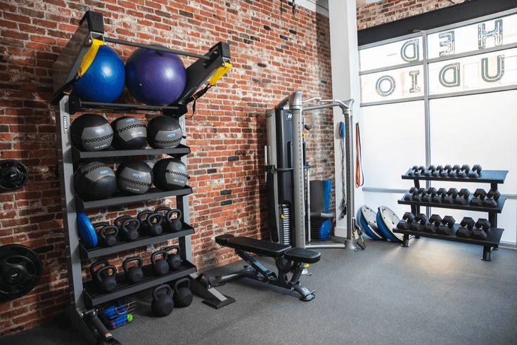 a gym with several exercise equipment in front of a brick wall