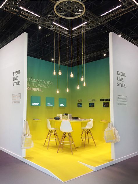 a yellow and white booth with chairs, tables and lights hanging from it's ceiling