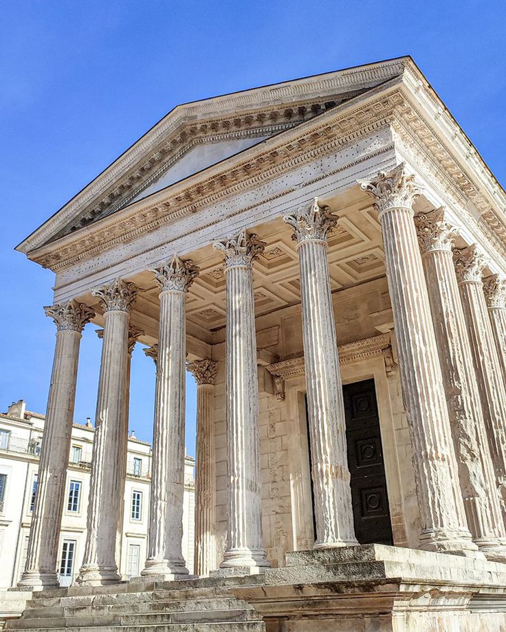 an old building with columns and pillars on the outside, in front of a blue sky