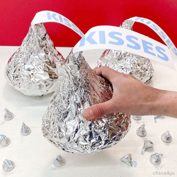 a hand is holding a piece of tinfoil over some silver foil with kisses on it