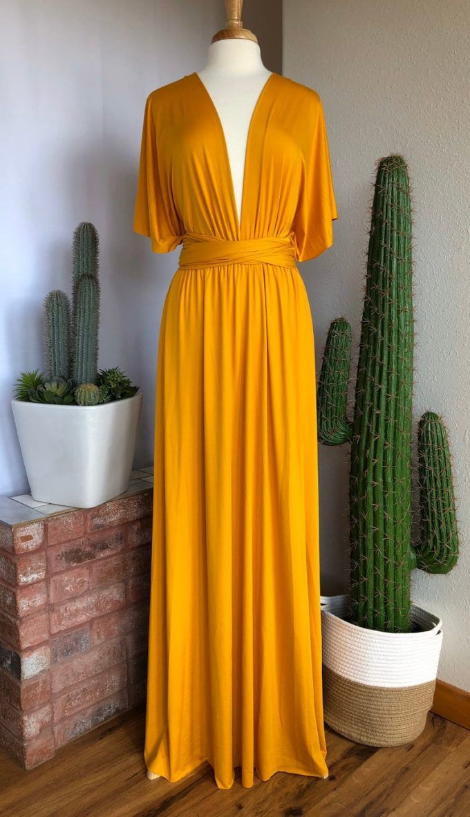 a yellow dress sitting on top of a wooden floor next to cacti and succulents