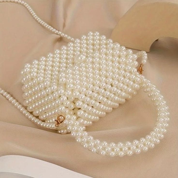 Why You'll Love It: Add a luxurious element to your style with this versatile faux pearl bag. The handmade craftsmanship guarantees a unique, high-quality accessory that is perfect for adding elegance to your everyday looks or standing out at special occasions. Key Features: *Material: High-quality faux pearls woven into a durable, elegant structure. *Versatile Style: Great for everyday use, weddings, parties, or adding a touch of elegance to any occasion. *Compact Size: Fits your essentials comfortably -- Dimensions: Height 19cm (7.48 inches), Length 15cm (5.91 inches), Width 7.5cm (2.95 inches). *Functional Design: Comes with a convenient handle and a long shoulder strap, giving you the option to carry it as a handbag or wear it as a crossbody. *Color: Available in a delicate pearl white Cream Bags With Pearl Handle, Fashion Cream Bag With Pearl Handle, Elegant Cream Bag, Elegant Cream Bags, White Bags With Pearl Chain, Cream Crossbody Shoulder Bag With Pearl Handle, White Pearl Bag With Pearl Chain, Elegant Crossbody Evening Bag With Pearl Handle, Elegant Pearl Handle Crossbody Evening Bag