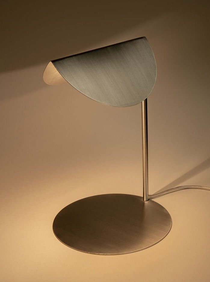 a table lamp that is on top of a white surface with a light coming from it