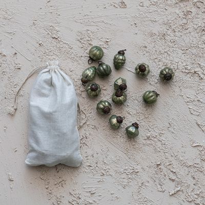 a bag full of green acorns sitting on top of a cement floor next to other small ones