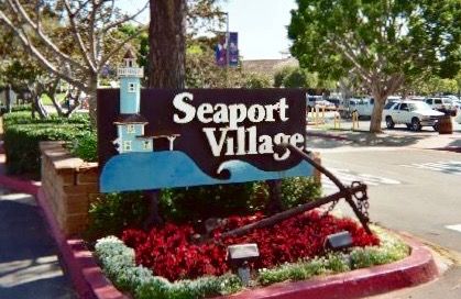 the sign for seaport village is shown in front of some trees and cars parked on the street