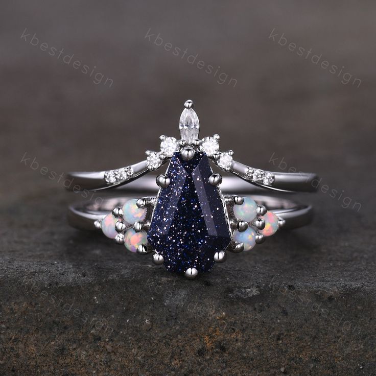 a diamond and blue stone ring sitting on top of a black surface with white diamonds