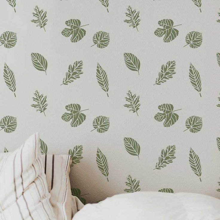 a white bed sitting next to a wall with green leaf decals on the walls