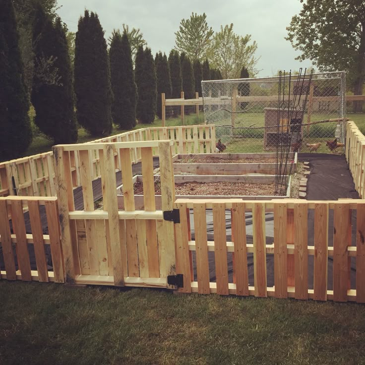 a wooden fence is in the middle of a yard with chicken coops on it