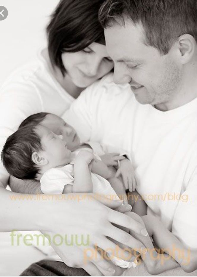 a man and woman holding a baby in their arms