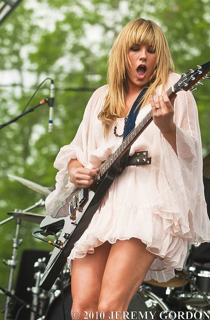 a woman in white dress playing guitar on stage