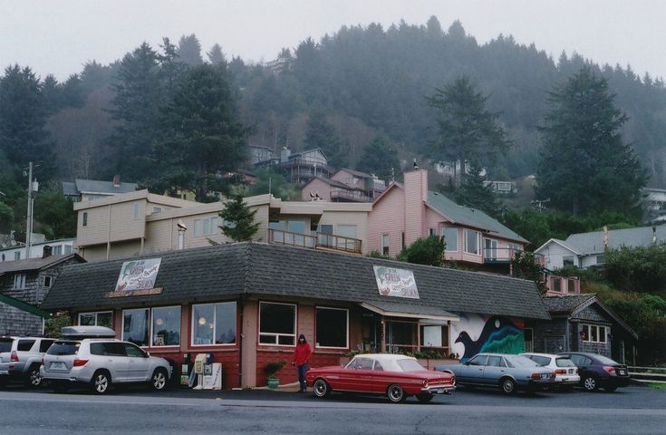 several cars are parked in front of a small restaurant on the side of a road