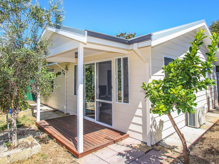 a small white house sitting on top of a wooden deck