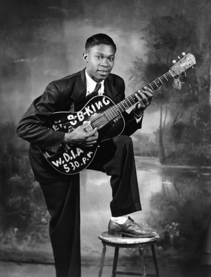 a black and white photo of a man holding a guitar