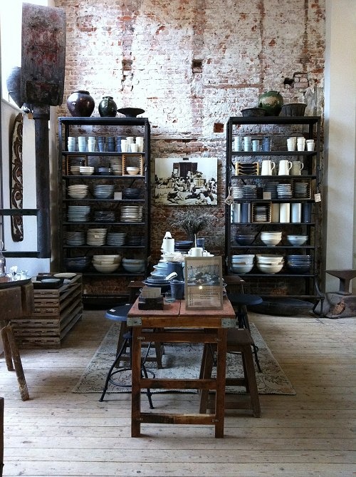 an old brick wall is filled with dishes and other items in this room, including shelves