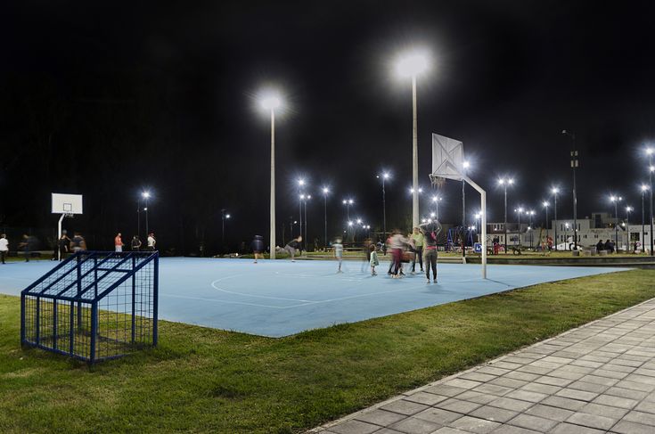 some people are playing basketball on a court in the dark at night with bright lights