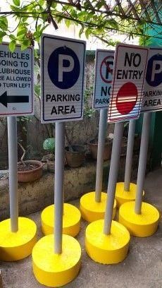 four parking signs are lined up in front of a building with trees and bushes behind them