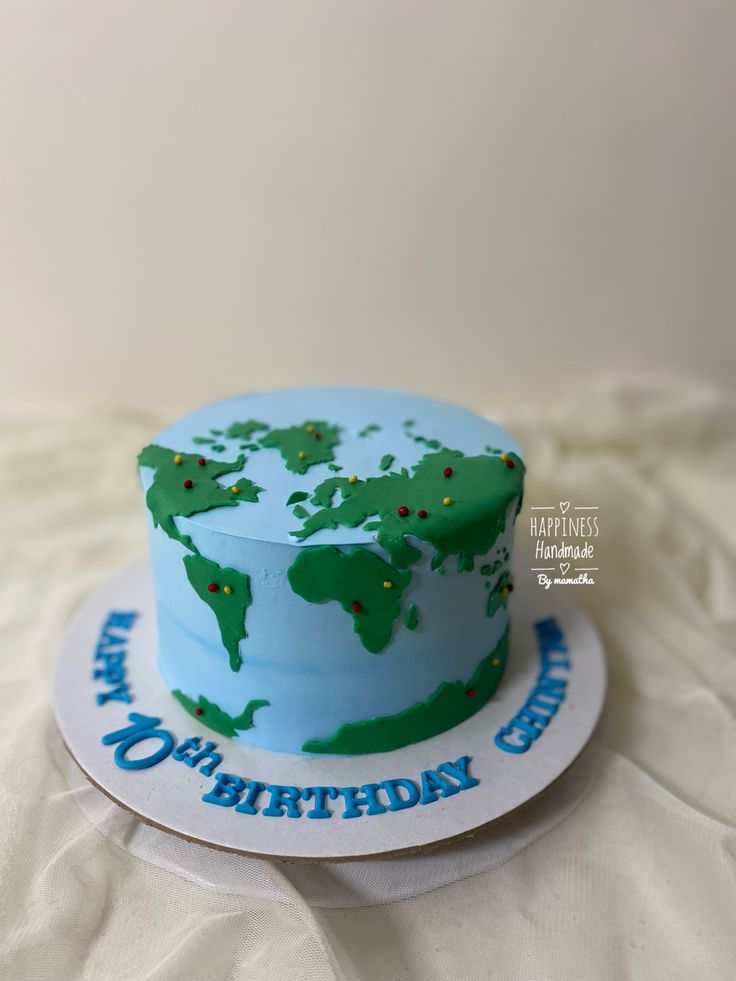 a blue and green birthday cake sitting on top of a white tablecloth covered surface