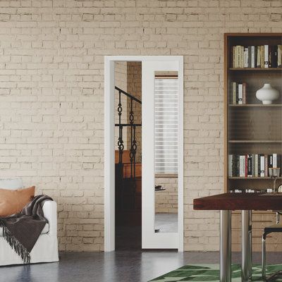 a living room filled with furniture and a book shelf next to a doorway that leads into a dining area