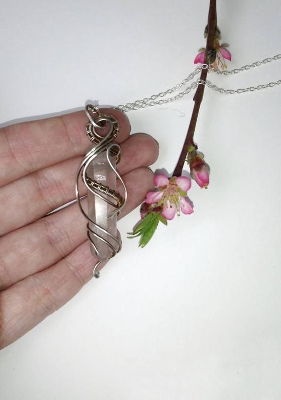 a hand holding a piece of jewelry with flowers on the end and a chain attached to it