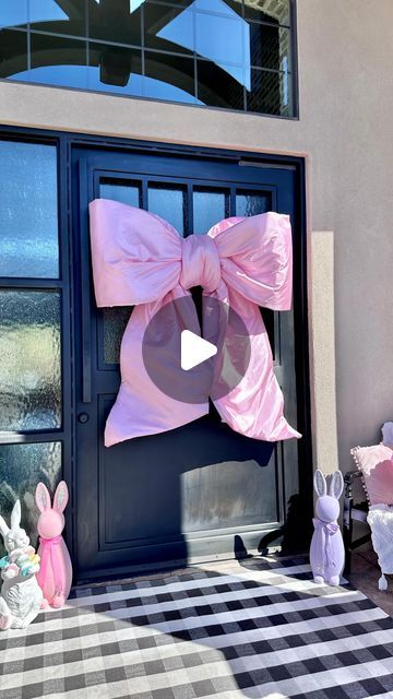 a large pink bow on the front door of a house with bunnies around it