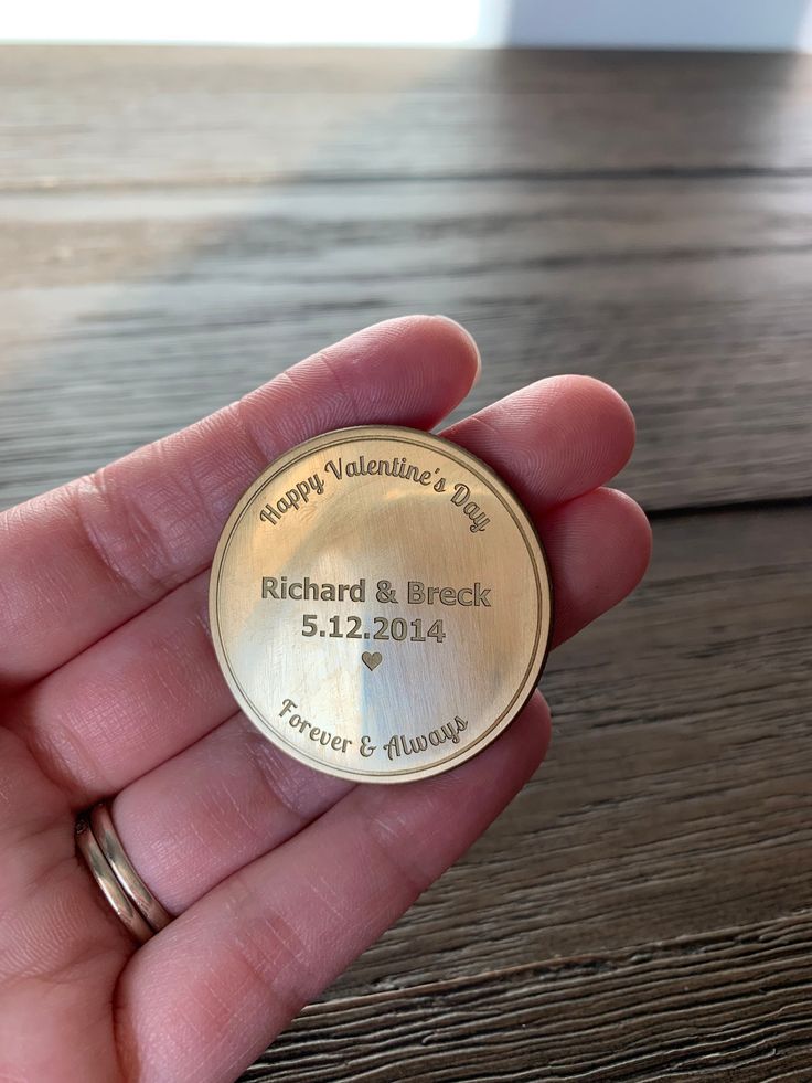 a person holding up a gold medal on top of a wooden table in their hand