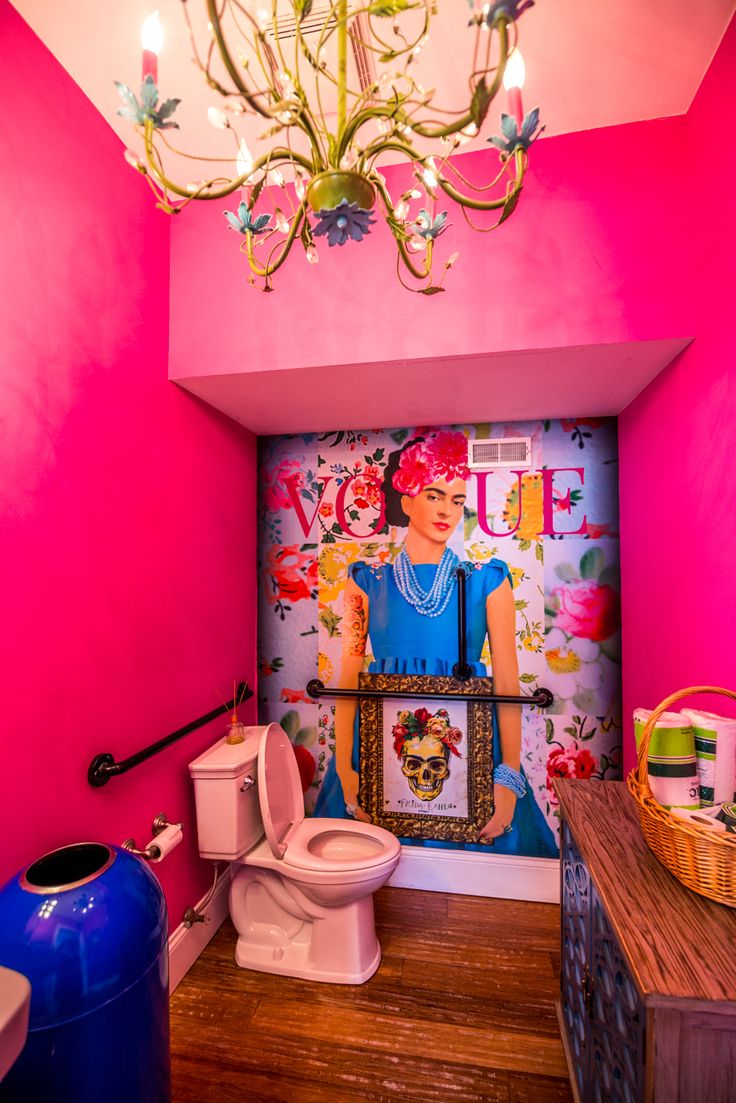 a pink bathroom with a chandelier hanging from the ceiling and a painting on the wall