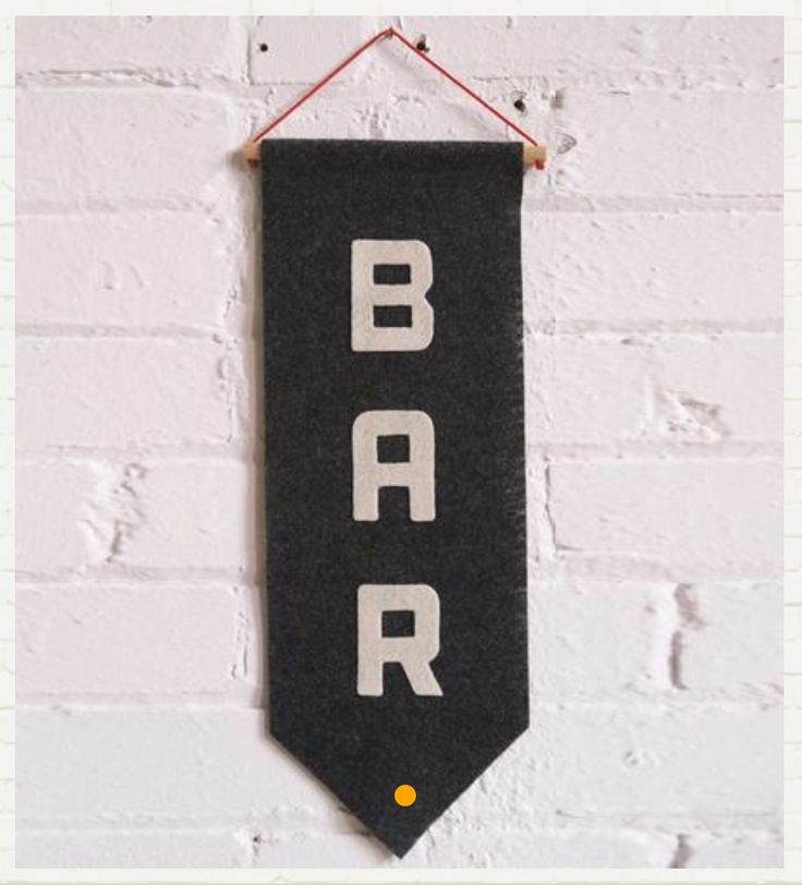 a black and white banner hanging from a brick wall with the word bar on it