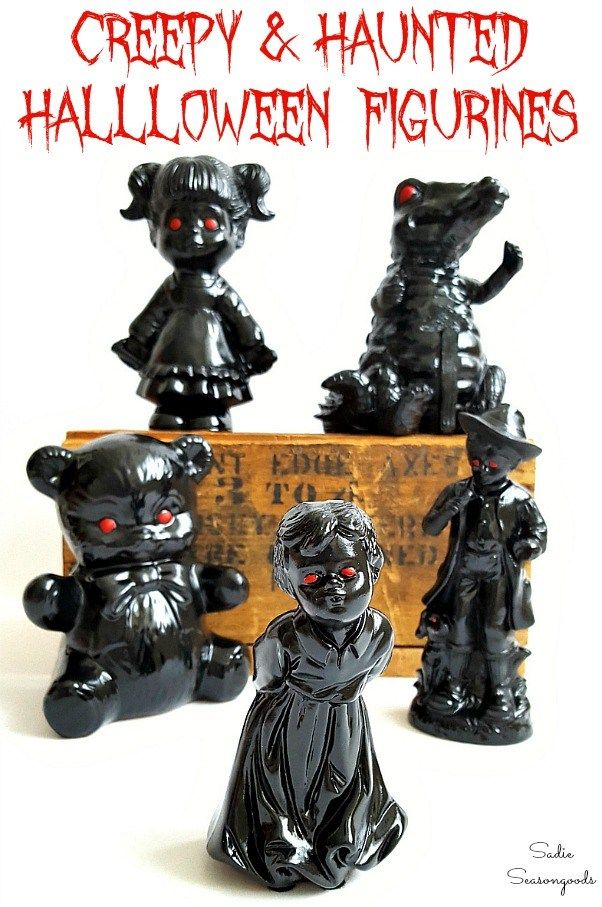 halloween figurines in black with red eyes and fangs on their faces, sitting next to a wooden box