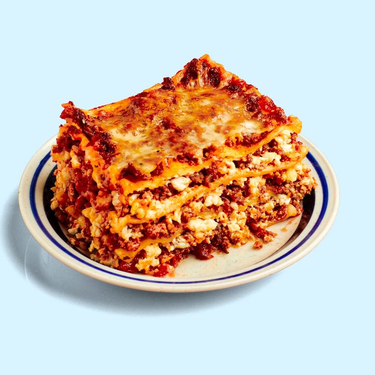 a white plate topped with lasagna covered in sauce and cheese on top of it