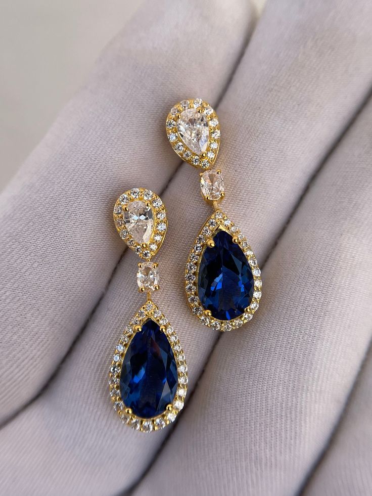 Luxury Blue Sapphire Earrings, Tear Drop Earrings, Pear Cut Earrings, Halo Earrings, 14k Solid Gold, Wedding Earrings, Engagement Earrings Handmade earring. Stone : Lab Blue Sapphire Gemstone Cut : Pear Cut Side Stone : Cubic Zirconia Metal  : 14k Gold / 925 Silver Plating : Platinum/Gold/Rose Gold Personalization: 10K/14K/24K/GOLD/SILVER/PLATINUM/ROSE-GOLD/WHITE GOLD. (Contact me)  All items come in a beautiful jewelry box.  Since all out Jewelry is Handmade with care and love, It takes [6-8 Business Days] to make the item. Once the item is made: Standard Shipping: 1-3 Weeks Express Shipping: 4-12 Days.  If you need anything personalized then you are MOST WELCOME. We specialized in personalized jewelry of all kinds, We have All Gemstones available as well as all Metals including White Gol Gold Sapphire Earrings, Luxury Blue Pear-shaped Earrings, Fine Jewelry Teardrop Bridal Earrings With Elegant Design, Teardrop Bridal Earrings With Elegant Design, Yellow Gold Drop Bridal Earrings For Formal Occasions, Formal Yellow Gold Drop Bridal Earrings, Formal Teardrop Bridal Earrings Pierced, Formal Teardrop Pierced Bridal Earrings, Formal Teardrop Bridal Earrings