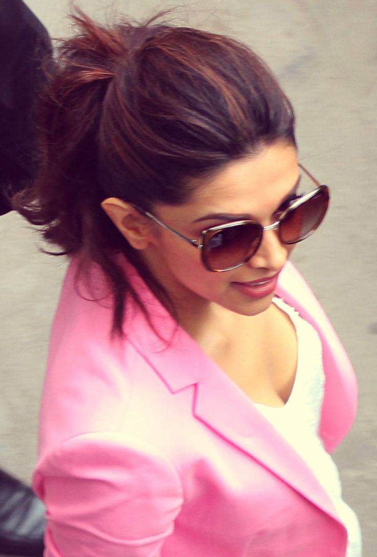 a woman in pink jacket and sunglasses walking down the street