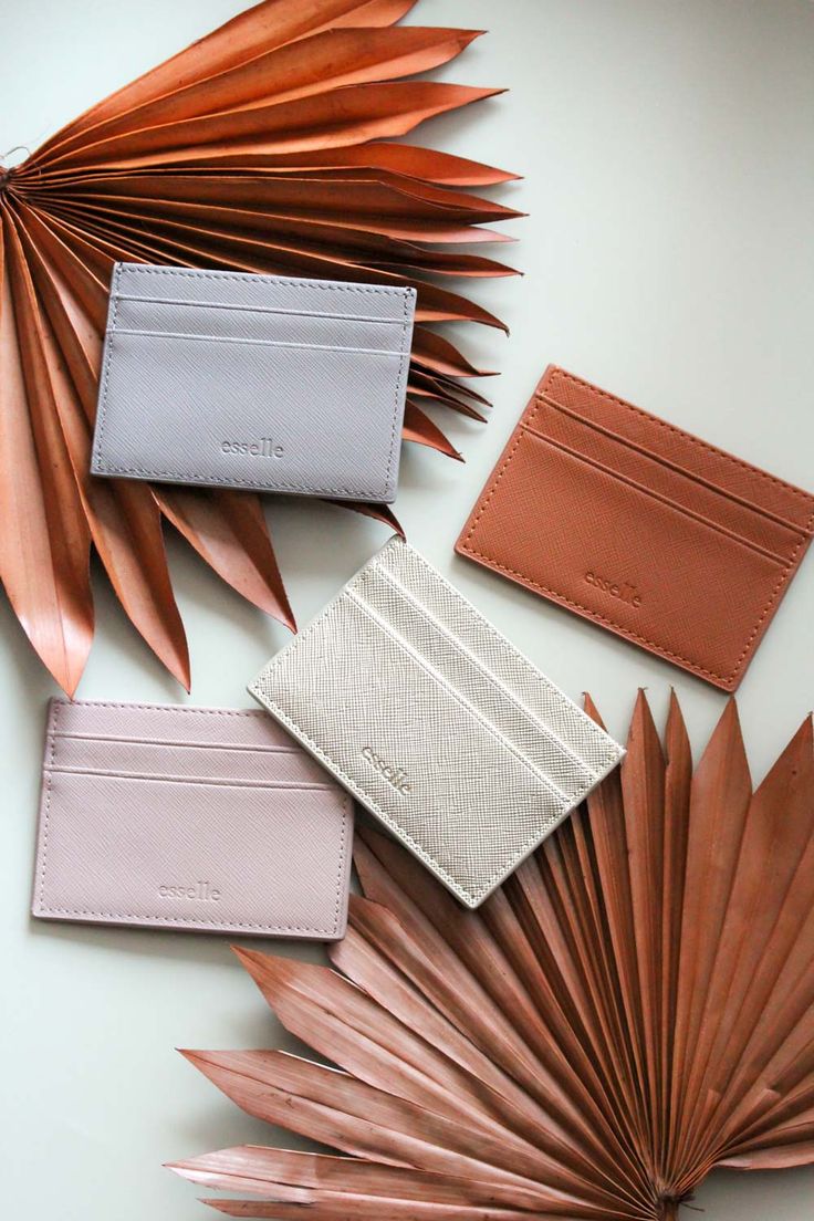 four different types of leather wallets laid out on top of each other with palm leaves