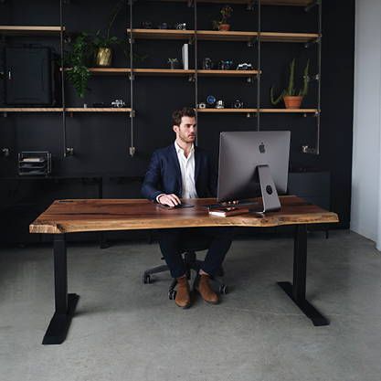 a man sitting at a desk with a laptop in front of him and shelves on the wall behind him