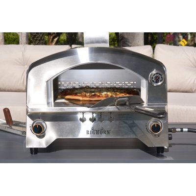 an outdoor pizza oven on a patio with couches in the backgroung