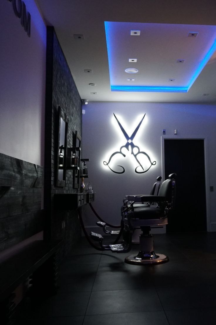 a barber shop with a large pair of scissors on it's wall next to a chair