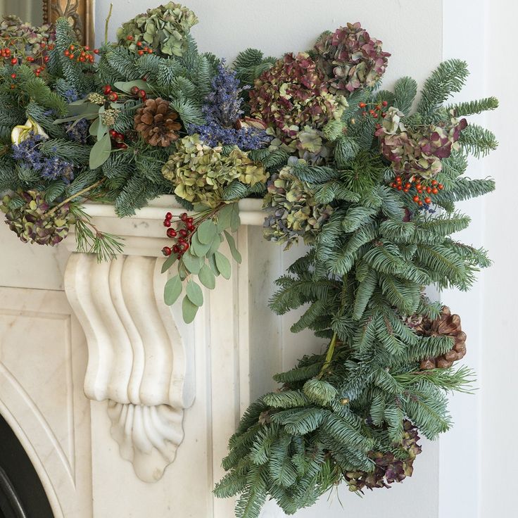 a christmas wreath is hanging on the mantle next to a fireplace mantel with greenery and pine cones